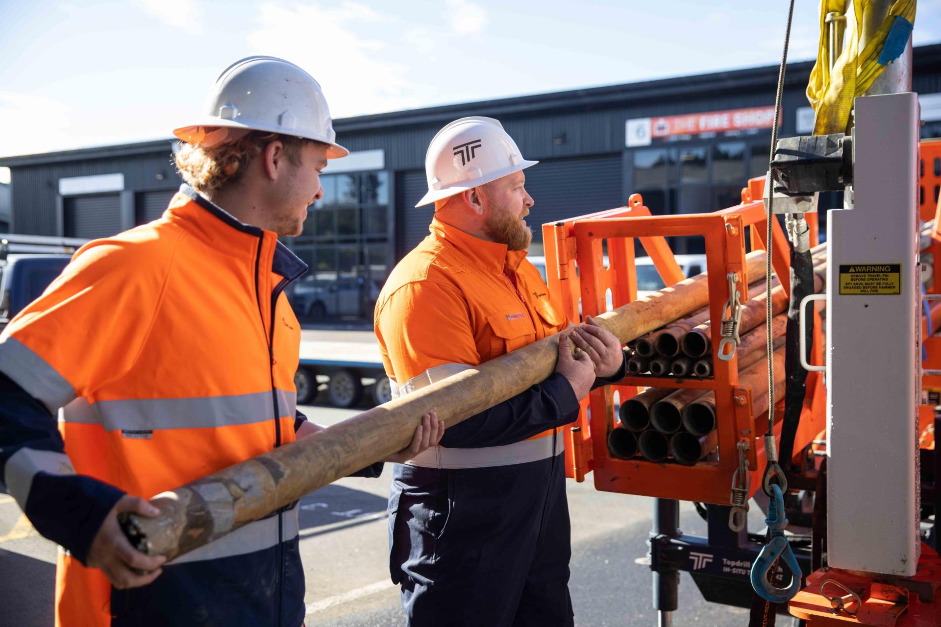 Two men loading materials onto borehole drilling machine