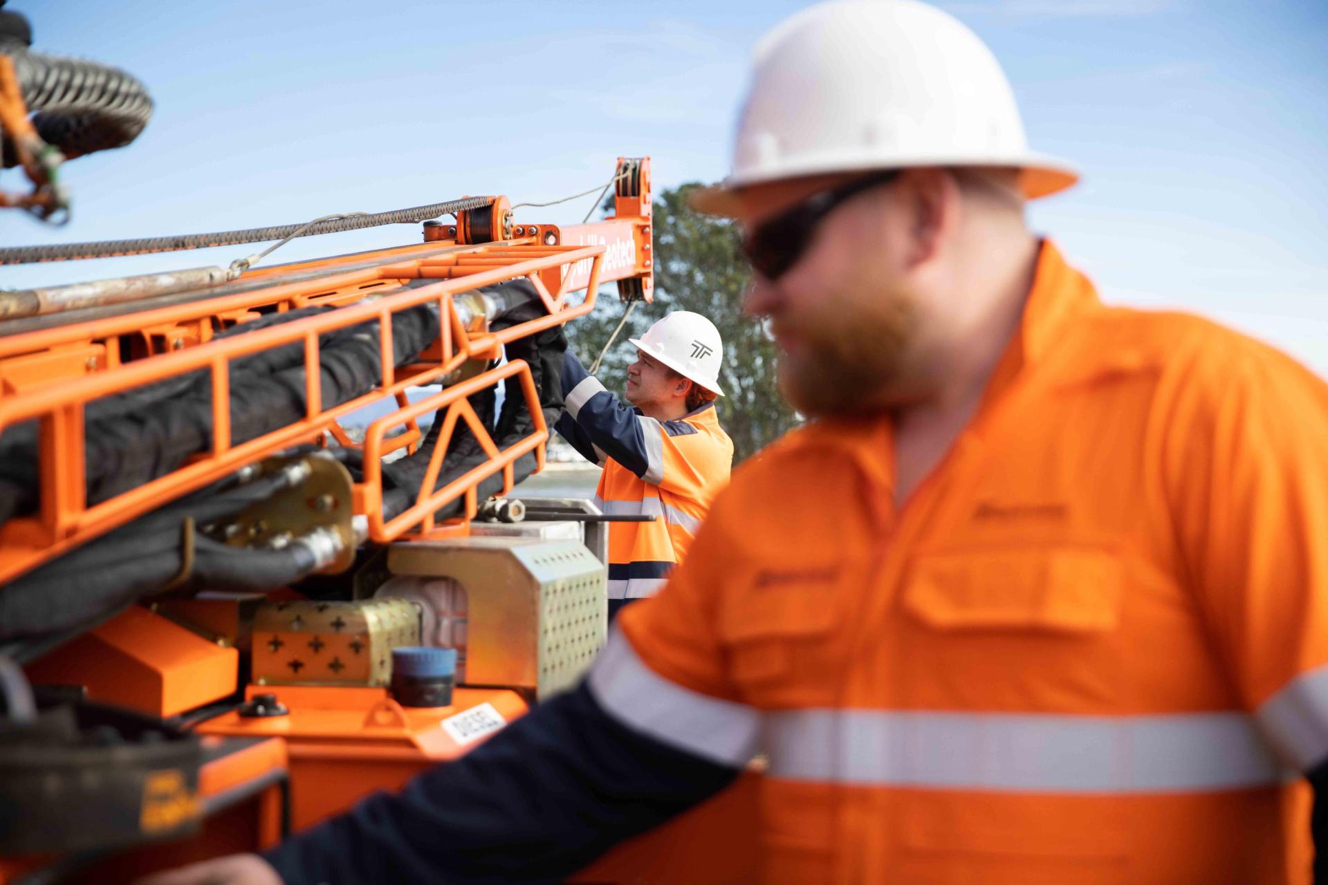 Two men working setting up a drilling machine