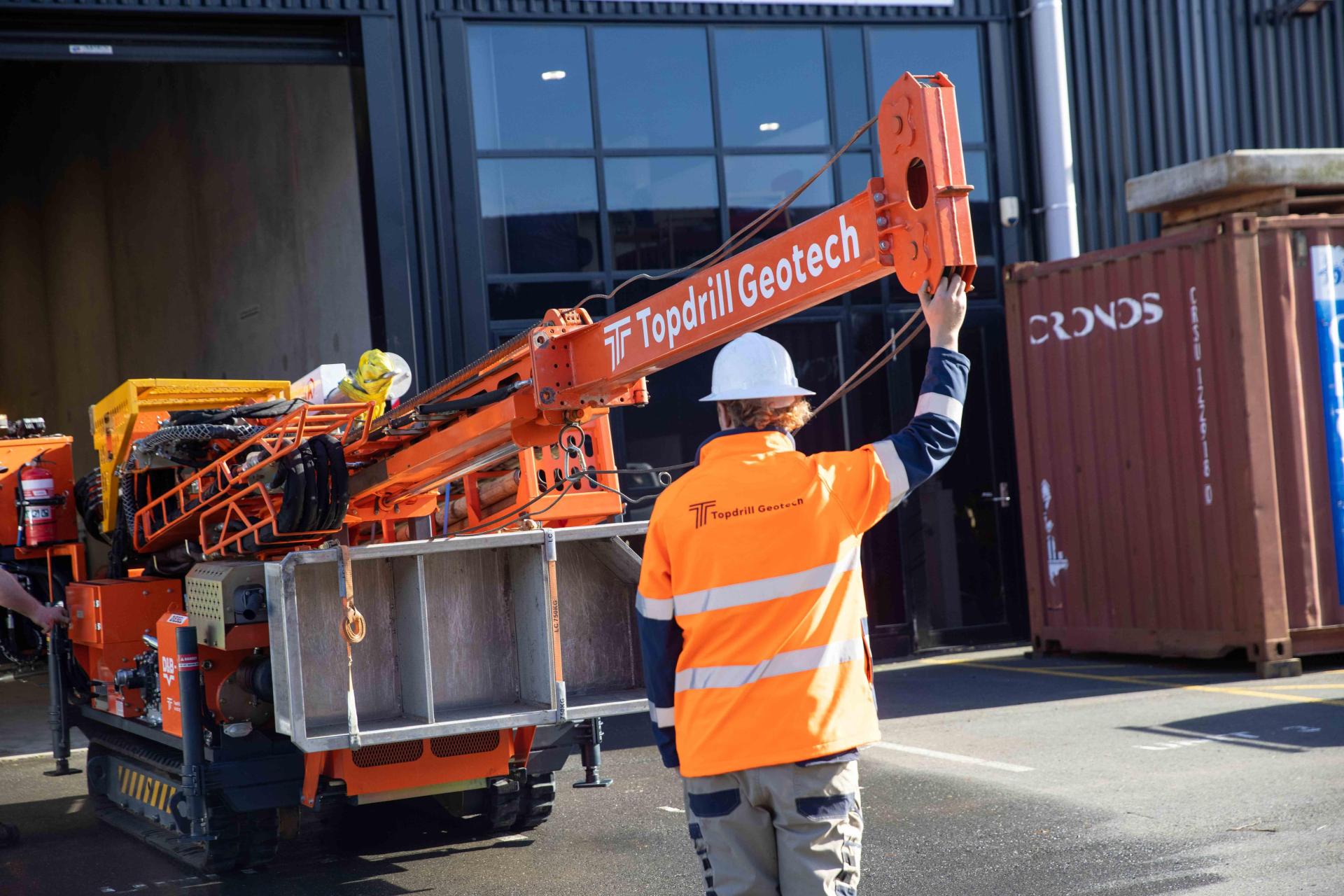 Man setting up borehole drilling machine in workshop yard