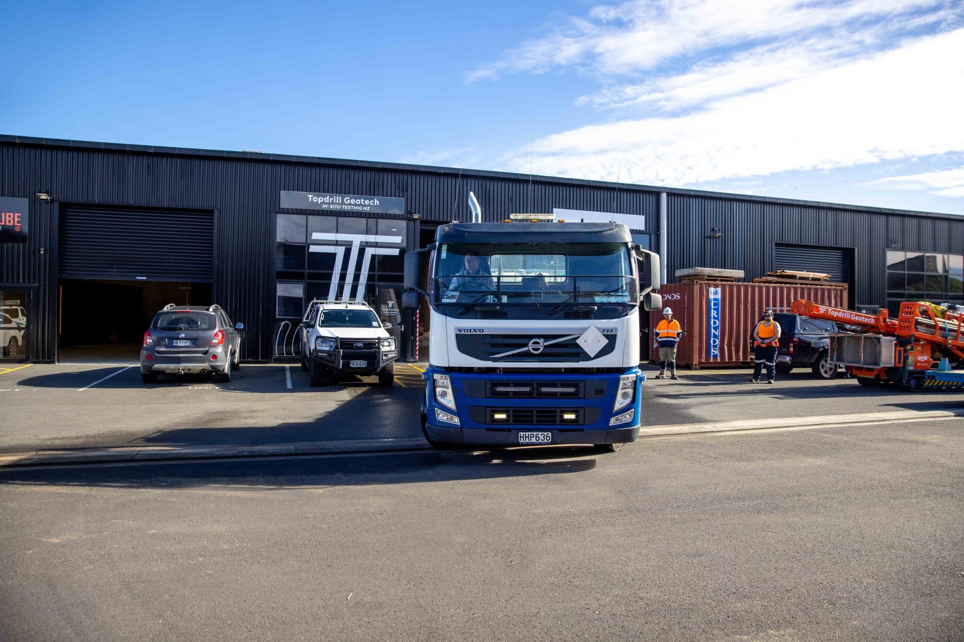 Truck, borehole drilling machine and other vehicles parked outside Topdrill workshop