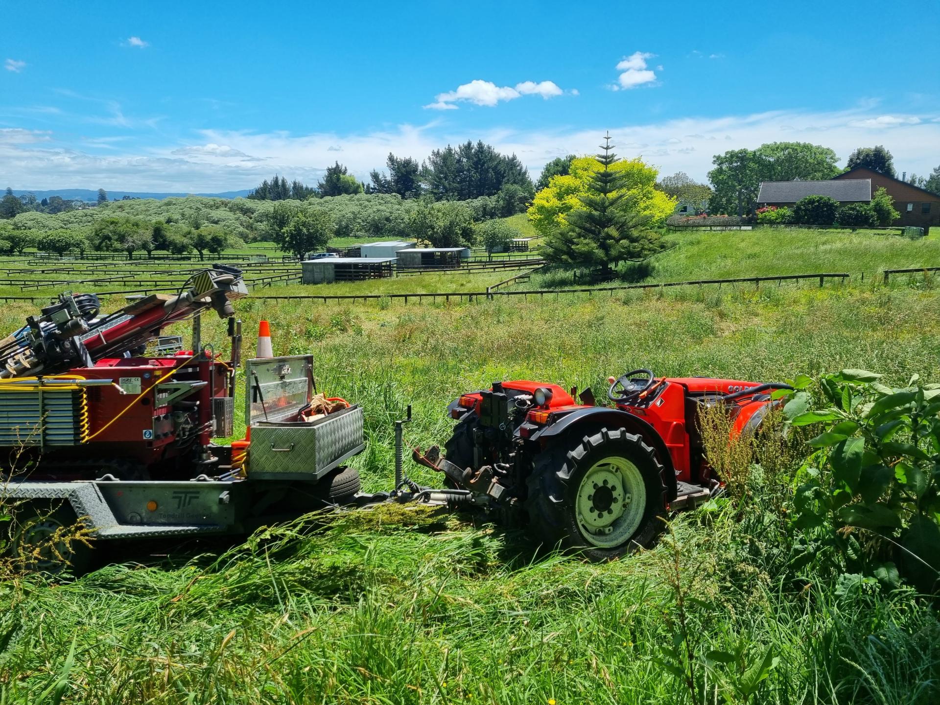 A tractor towing a CPT machine on a trailer through a field